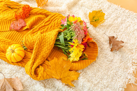 Knitted cardigan, bouquet of flowers and autumn decor on light plaidの写真素材