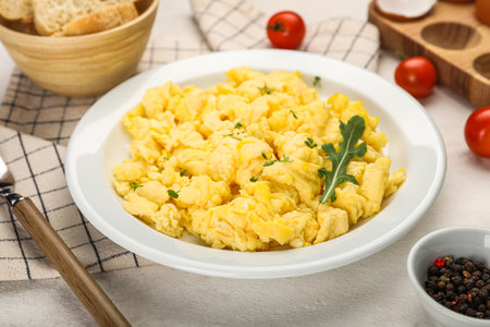 Plate of tasty scrambled eggs on light table, closeupの写真素材