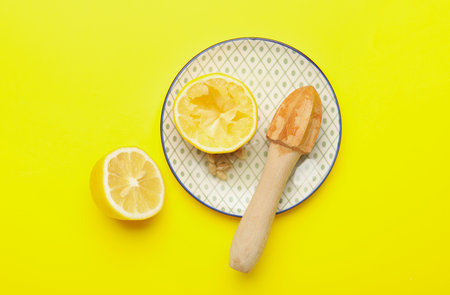 Plate with fresh lemon and wooden juicer on yellow backgroundの写真素材