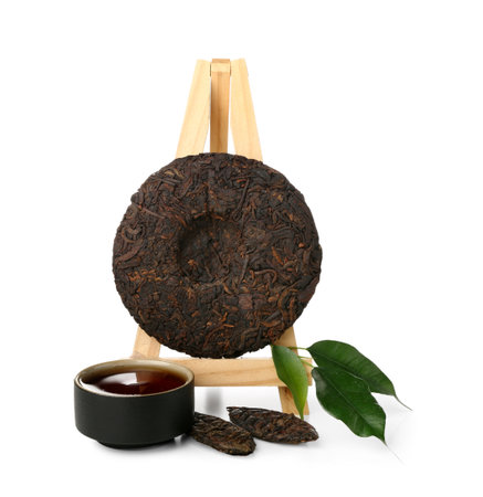 Stand with dry pressed puer tea, leaves and cup on white backgroundの写真素材