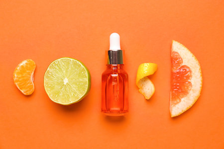 Composition with bottle of citrus serum and fruits on color backgroundの写真素材