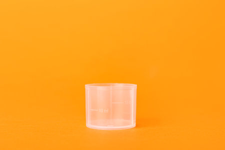 Empty measuring cup on orange backgroundの写真素材