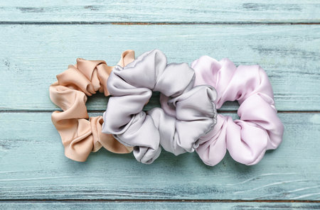 Silk scrunchies on green wooden background