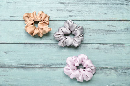 Silk scrunchies on green wooden background
