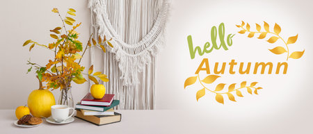 Beautiful composition with tree branches, books and cup of coffee on table in room. hello autumn