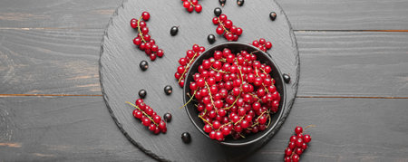 Bowl of ripe red currant on wooden background, top viewの写真素材