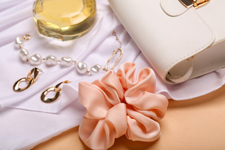 Stylish female accessories, clothes and perfume bottle on beige background