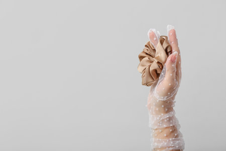 Female hand in glove with silk scrunchy on light backgroundの写真素材