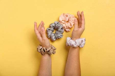 Female hands with silk scrunchies on yellow backgroundの写真素材