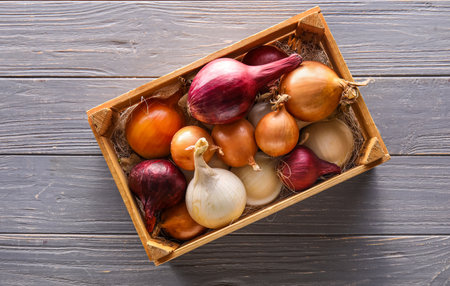 Box with different kinds of onion on dark wooden backgroundの写真素材