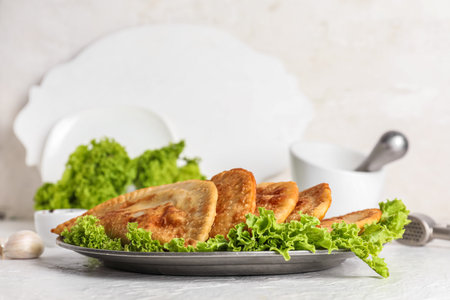 Plate with tasty chebureks and lettuce on light backgroundの写真素材