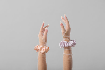 Female hands in gloves with silk scrunchies on light backgroundの写真素材