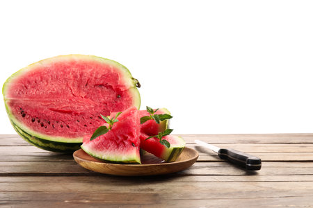Plate with slices of watermelon, mint and knife on table against white backgroundの写真素材