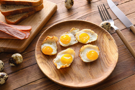 Plate with tasty fried quail eggs on wooden table, closeupの写真素材
