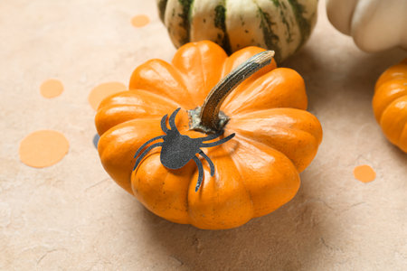 Halloween pumpkin with spider on beige background, closeup