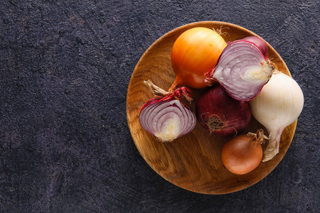 Wooden plate with fresh onion on dark backgroundの写真素材