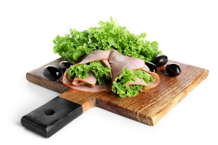 Wooden board with slices of tasty ham and lettuce on white backgroundの写真素材