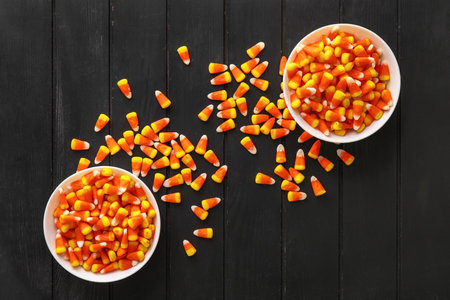 Bowls with Halloween candy corns on black wooden background