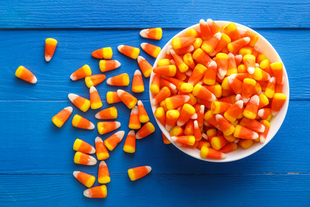 Bowl with Halloween candy corns on blue wooden backgroundの写真素材