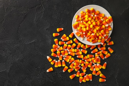 Plate with Halloween candy corns on black background