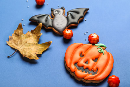 Tasty Halloween cookies, candies and fallen leaf on blue background, closeupの写真素材