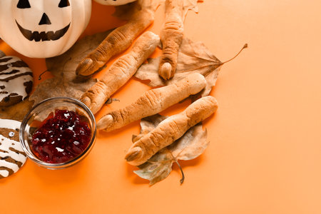 Halloween cookies with fallen leaves, bowl of jam and pumpkin on orange backgroundの写真素材