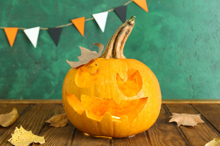 Jack-O-Lantern pumpkin on table near green wallの写真素材