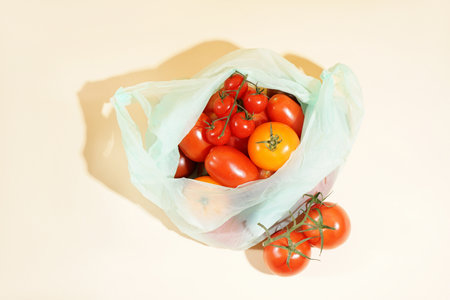 Bag with fresh ripe tomatoes on light backgroundの写真素材