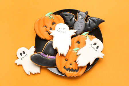 Plate with tasty Halloween cookies on orange backgroundの写真素材