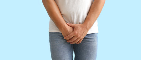 Man with prostate problem on light blue background, closeup