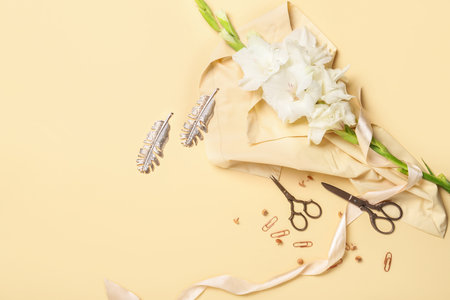 Scissors, ribbon, flowers and stationery supplies on color backgroundの写真素材