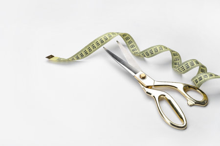 Scissors and measuring tape on white background