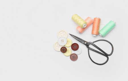 Scissors, buttons and spools of thread on white background