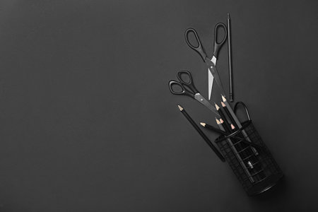 Overturned holder for stationery supplies, scissors and pencils on black backgroundの写真素材