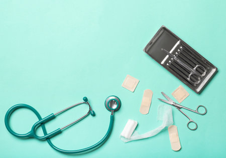 Stethoscope, surgical scissors, medical plasters and gauze roll on color backgroundの写真素材