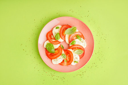 Plate of tasty caprese salad on green backgroundの写真素材