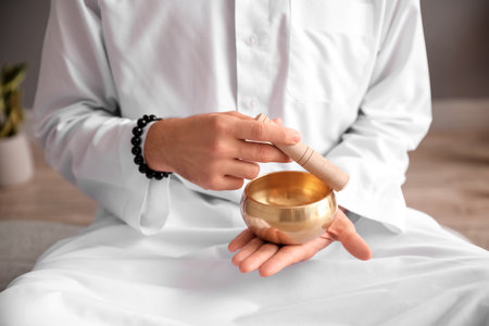 Man with Tibetan singing bowl at home, closeupの写真素材
