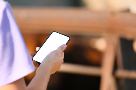 Young female worker with mobile phone near paddock on farmの写真素材