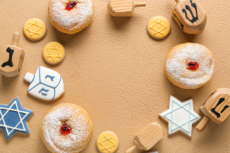 Frame made of wooden dreidels, cookies and donuts for Hanukkah celebration on color backgroundの写真素材