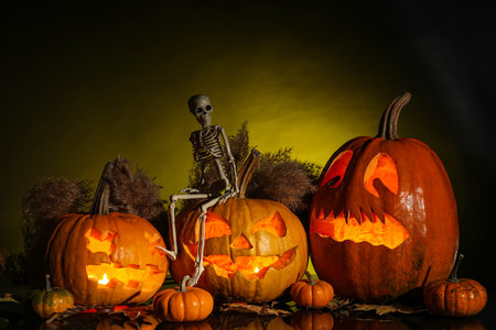 Carved Halloween pumpkins with skeleton and pampas grass on dark backgroundの写真素材