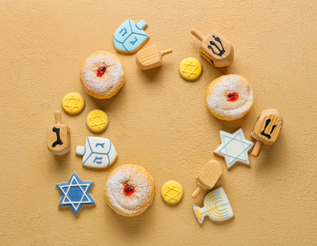 Frame made of dreidels, cookies and donuts for Hanukkah celebration on color backgroundの写真素材