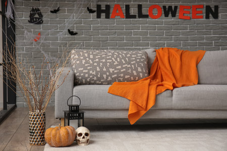 Interior of living room decorated for Halloween with gray sofa and tree branches in vaseの写真素材
