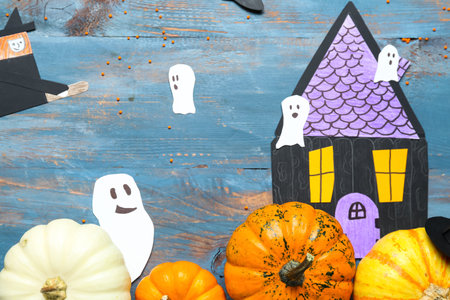 Halloween pumpkins with paper decor on blue wooden background