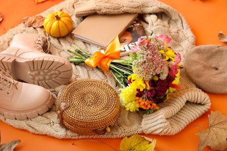 Knitted sweater, stylish female accessories, bouquet of flowers and autumn leaves on orange...