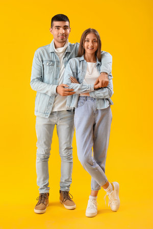 Fashionable young couple in autumn clothes on yellow backgroundの写真素材