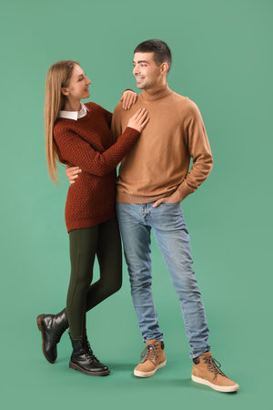 Fashionable young couple in autumn clothes on green backgroundの写真素材