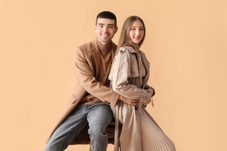 Fashionable young couple in autumn clothes on beige backgroundの写真素材