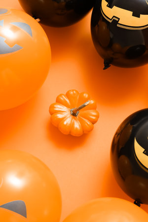Ripe pumpkin and Halloween balloons on color background, closeupの写真素材