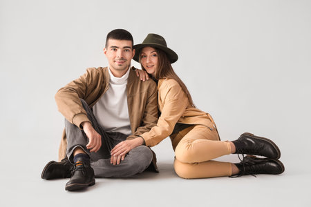 Fashionable young couple in autumn clothes on light backgroundの写真素材