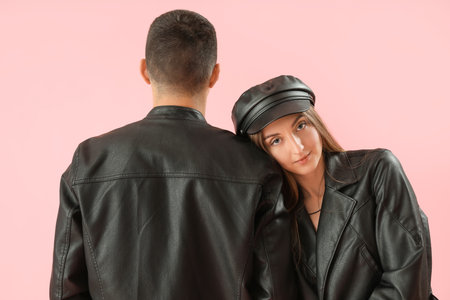 Fashionable young couple in autumn clothes on pink backgroundの写真素材